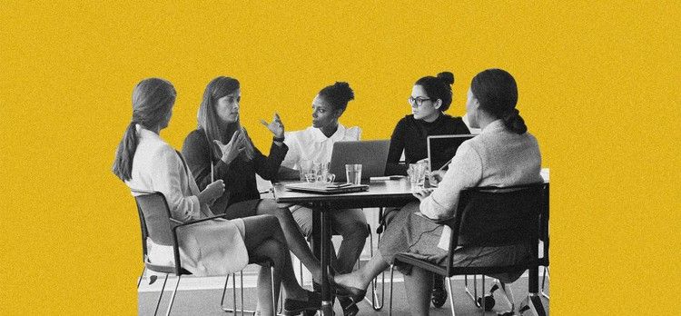 Cinq femmes sont assises autour d'une table, en pleine discussion, avec devant elles des ordinateurs portables, des cahiers et des verres d'eau, sur un fond jaune.